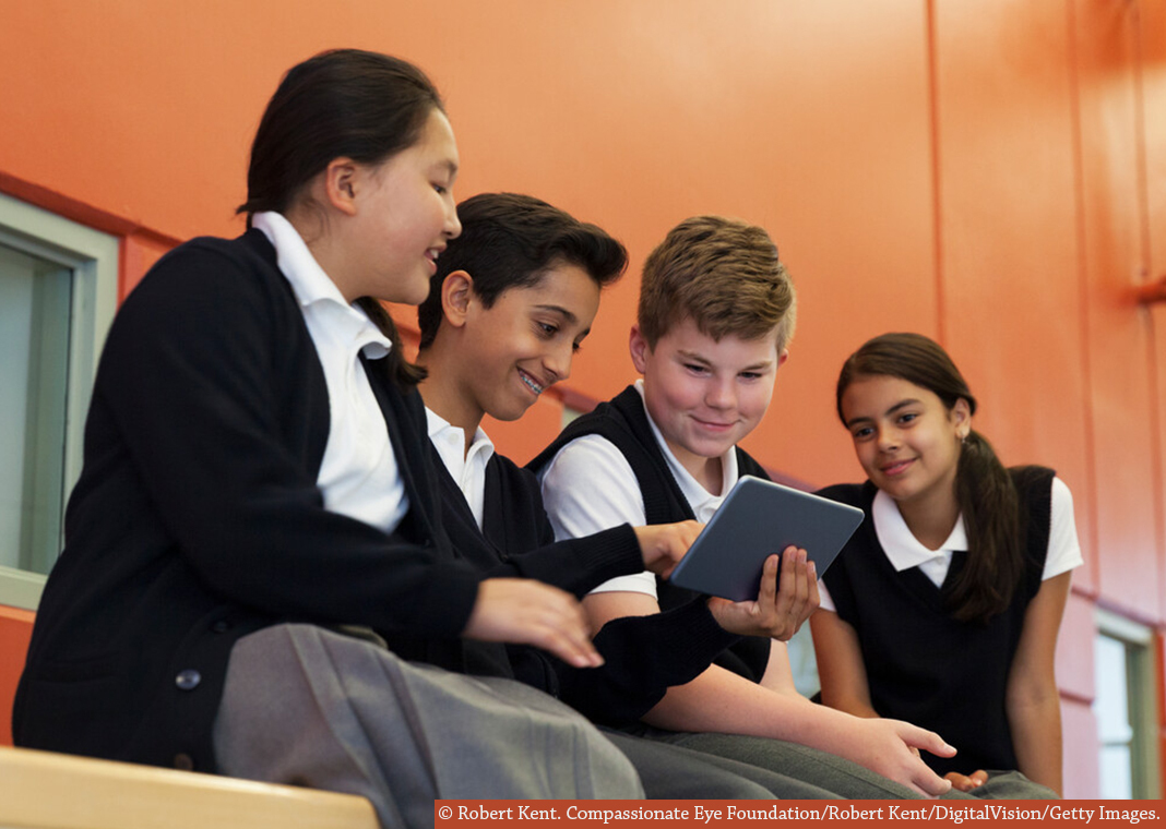 Catholic school students on tablet - © Robert Kent. Compassionate Eye Foundation/Robert Kent/DigitalVision/Getty Images.