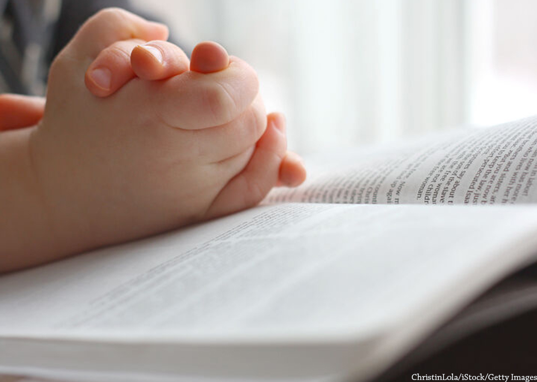 child's hands folded over Bible - ChristinLola/iStock/Getty Images